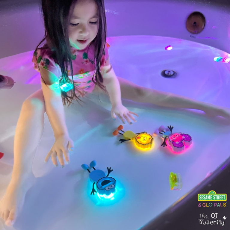 Toddler playing with glow up sensory toys in a bath tub